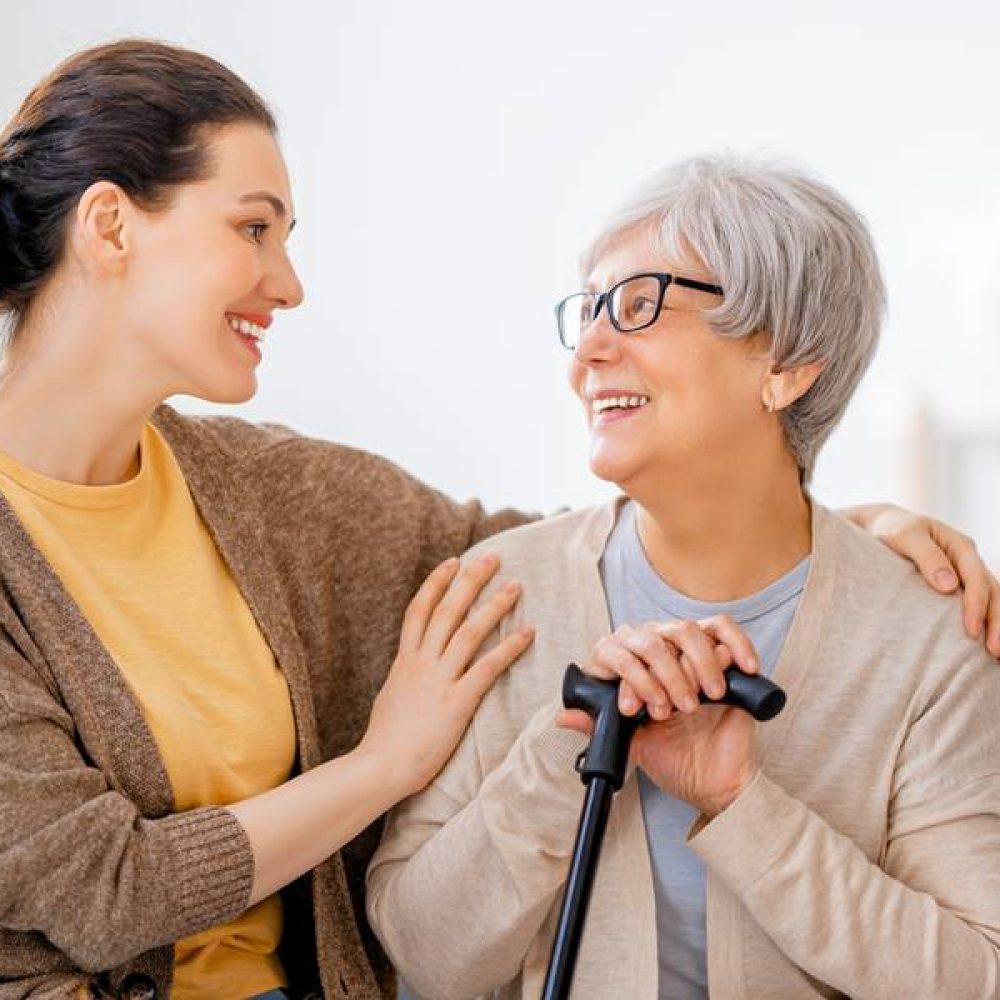 Happy patient and caregiver spending time together. Senior woman holding cane.